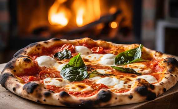 A tantalizing image of a freshly-baked Pizza Napoletana. The pizza sits against the rustic backdrop of a traditional Neapolitan pizzeria, with the wood-fired oven visible in the background. The vibrant red of the tomato sauce, the creamy white of the buffalo mozzarella, and the fresh green basil leaves create a visual feast that mirrors the delectable dish itself